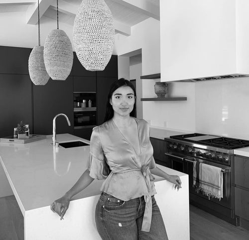 black and white image of woman in blouse and jeans standing in kitchen