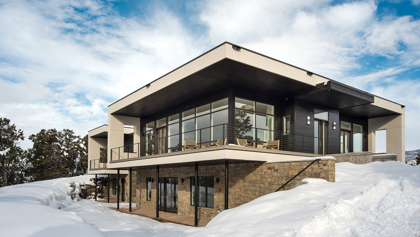 exterior view of modern home with glass walls and snow