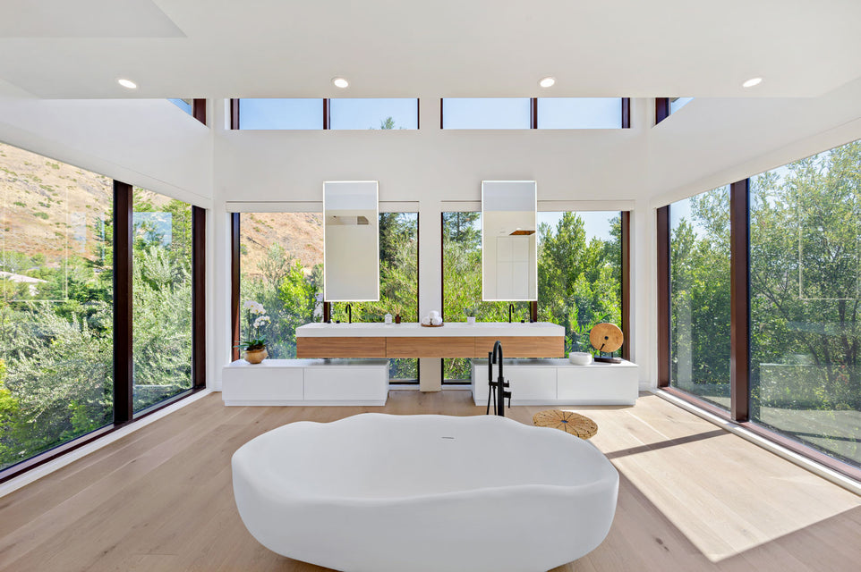 bathroom with bathtub, double sink and high glass walls