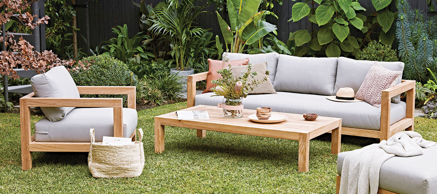 outdoor grass area with gray furniture and wooden coffee table