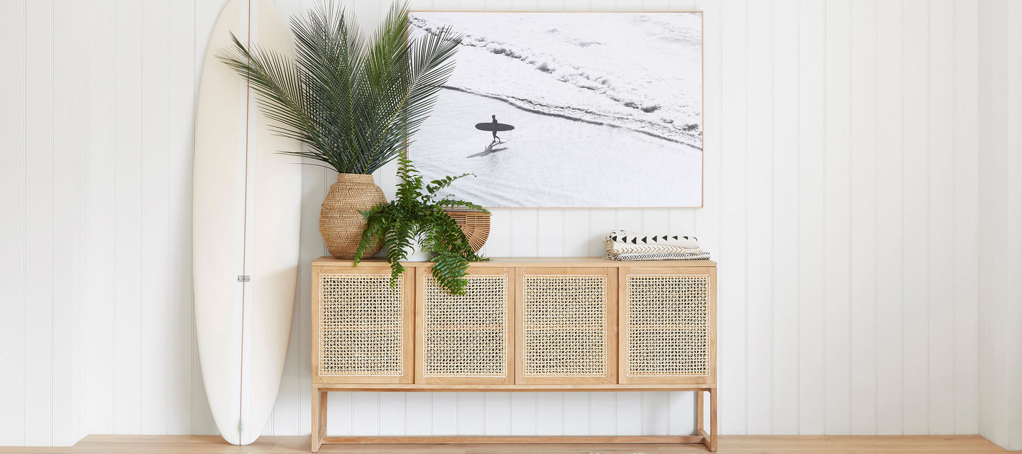 wooden credenza with white surfboard and potted plants against white background